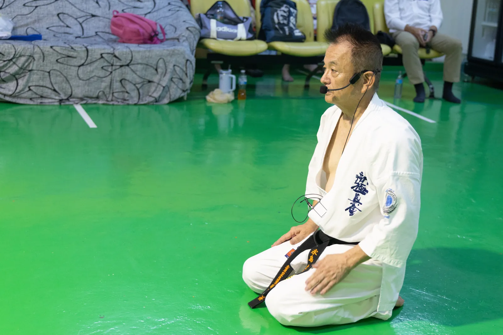Shihan Nagashima นั่งเซซะและก้มมองมือของตัวเอง ระหว่างอธิบายลำดับการลุกนั่ง