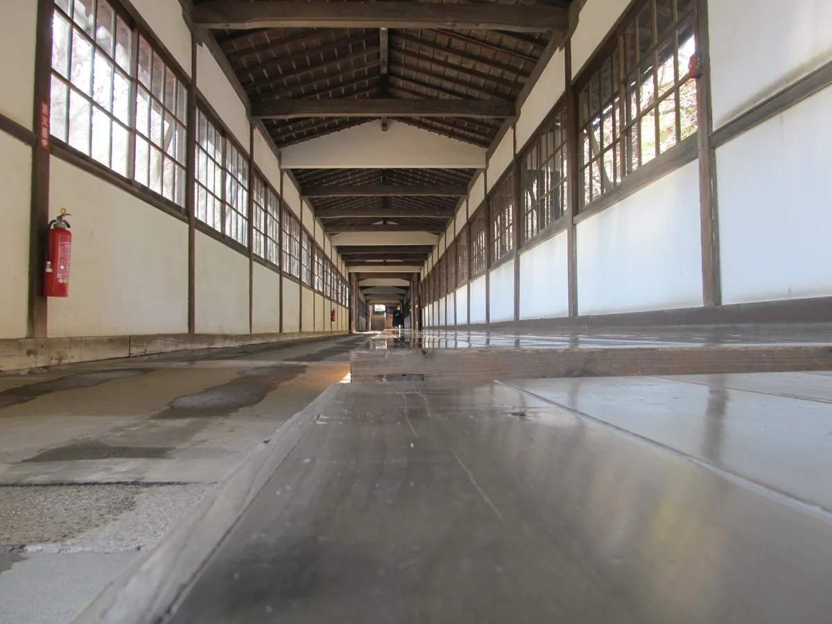 A long wooden temple corridor with wet lines left by rag-wiping