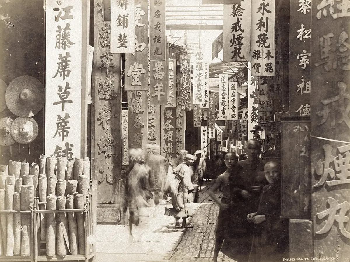 黑白照片:中国城市里的一条窄街,两旁挂满店铺招牌,行人往来