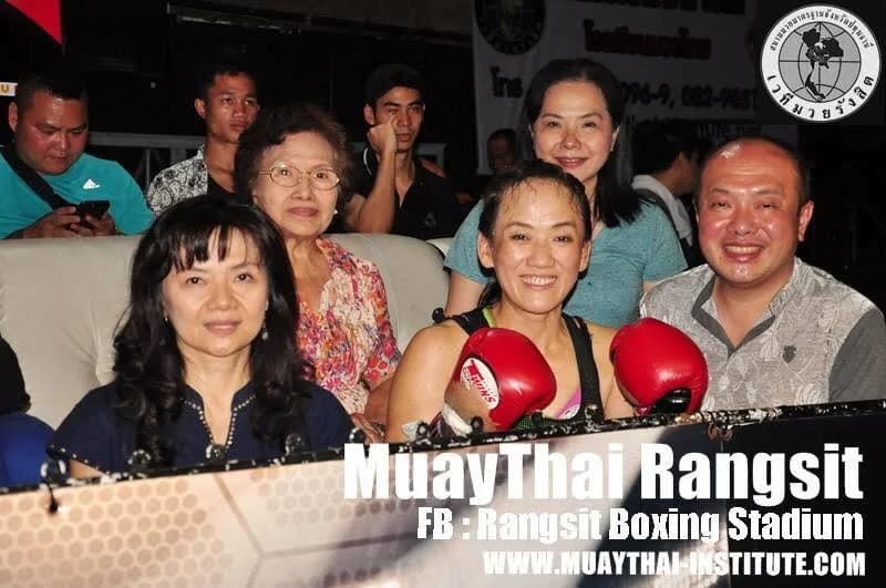 赤いムエタイグローブを着けた Khru 方淑燕と、リングサイドで応援に訪れた人たち