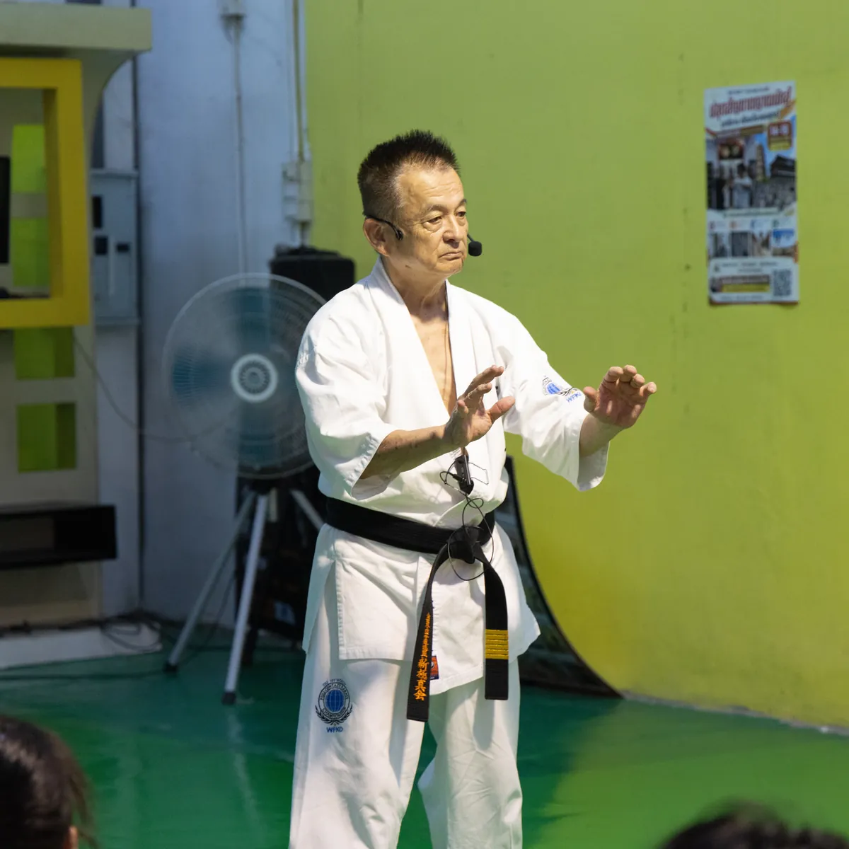 Shihan Nagashima ยกมือทั้งสองข้างระดับหน้าท้อง อธิบายการควบคุมตันเถียนให้นักเรียน วันที่ 18 กันยายน พ.ศ. 2569