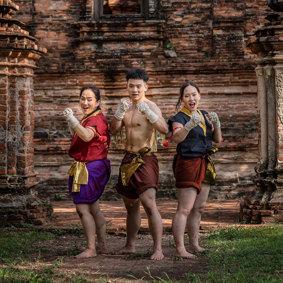 Wai Kru Muay Thai students posing in traditional training outfits at an ancient brick temple