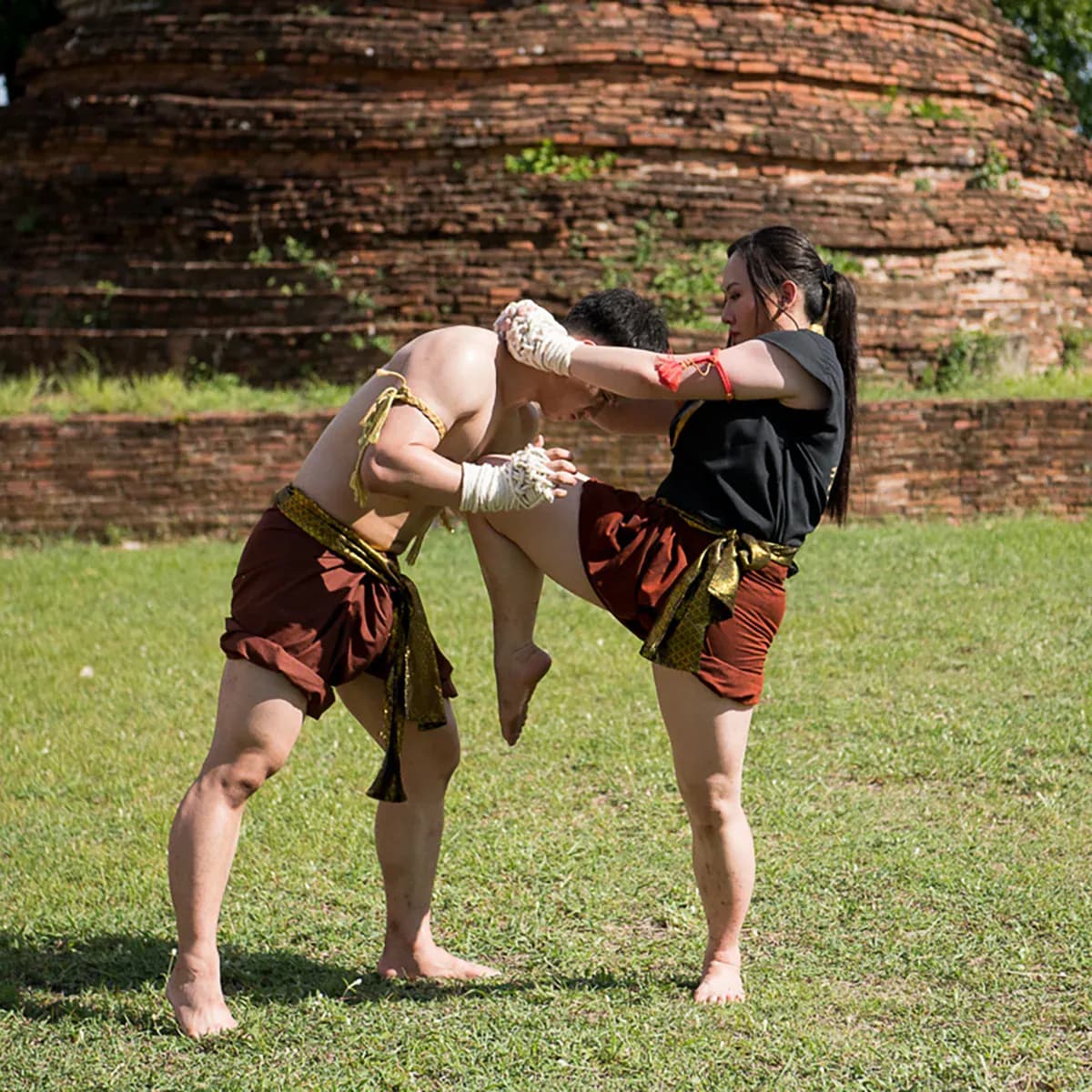 นักเรียนไหว้ครูมวยไทยฝึกเข่าและท่าการ์ดหน้าพระเจดีย์อิฐโบราณ
